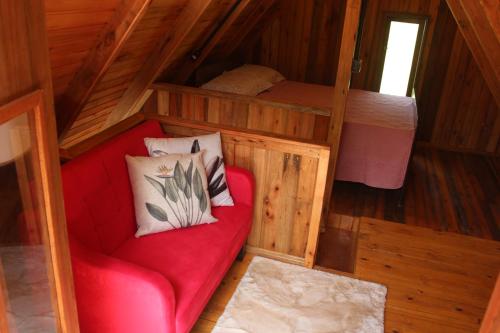 a red couch with two pillows in a cabin at Vila Sol Cabanas in Lontras