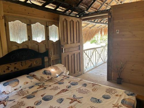 1 dormitorio con 1 cama y puerta al porche en Punta Arena EcoHostal and EcoFit – Your Eco-Friendly Oasis 02, en Cartagena de Indias