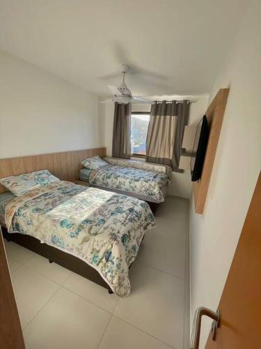 a small room with two beds and a window at Apartamento em Praia Grande in Arraial do Cabo