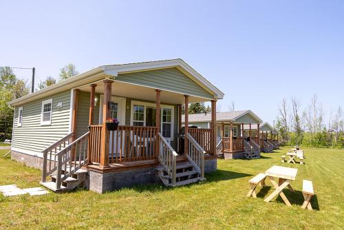 a small house with a porch and a picnic table at Fiddler's Green Country Cottages in Brackley Beach