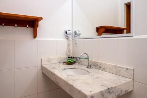 y baño con lavabo de mármol y espejo. en Pousada Pé na Terra, en Brotas