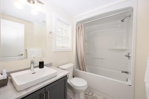 Baño blanco con lavabo y aseo en Fiddler's Green Country Cottages, en Brackley Beach