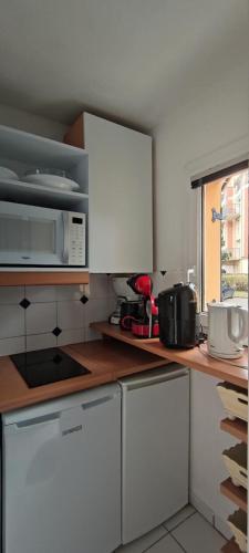 une cuisine avec des armoires blanches et un micro-ondes dans l'établissement Les maisons de Port Guillaume - maeva Home - Maison 3 Pièces 6 Personnes Sélection MAE-2279, à Dives-sur-Mer