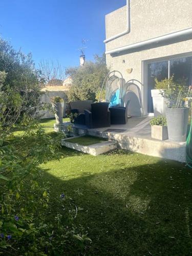 een tuin met stoelen en planten op een huis bij Villa à 10 minutes de Nîmes in Marguerittes