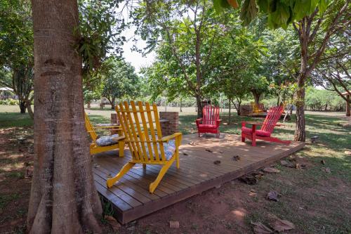 a group of chairs sitting on a wooden deck next to a tree at Pousada Pé na Terra in Brotas