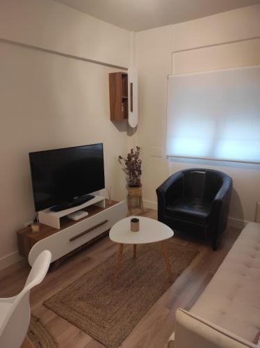 un salon avec une télévision et une chaise noire dans l'établissement Apartamento Casa Ryo, à Santander