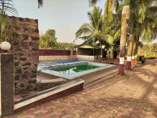 a swimming pool in a courtyard with palm trees at Nargis Farm Resort in Vihur