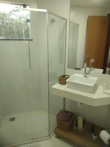 a bathroom with a sink and a shower with a mirror at Morada Góes Calmon in Itabuna