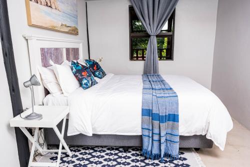 um quarto com uma cama, uma mesa e uma janela em Seloko Guest Cottage em Polokwane