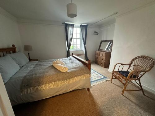 a bedroom with a bed and a chair and a window at Nutshell Cottage in Seaton