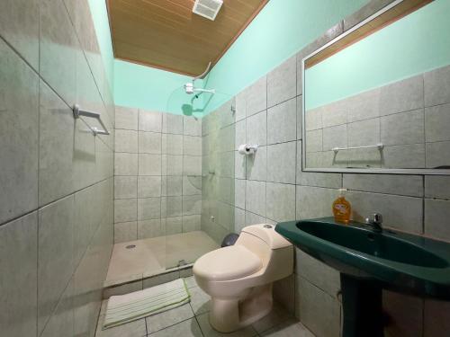 a bathroom with a sink and a toilet and a mirror at Casa Quepos in Quepos