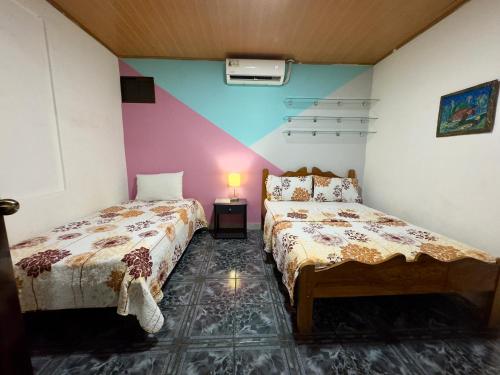 a bedroom with two beds and a lamp on a table at Casa Quepos in Quepos