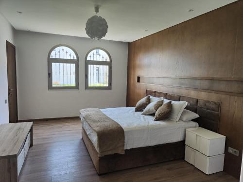a bedroom with a large bed and two windows at Maison Front de mer in Martil