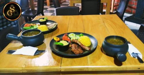 a wooden table with two plates of food on it at Suite Gold Hotel Omaga in El Peñol