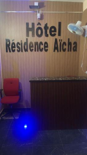 une chaise rouge dans une pièce avec un signe alpha de résistance à l'honneur dans l'établissement Hôtel Résidence Aïcha Tambacounda, à Tambacounda