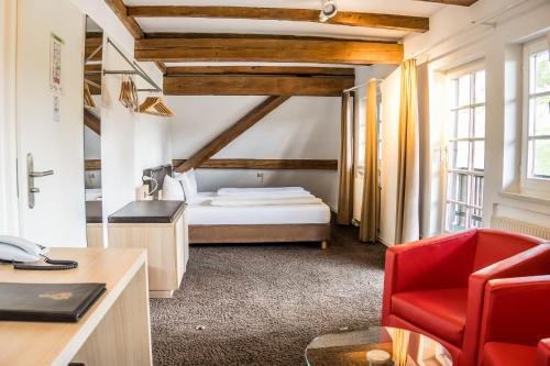 Habitación de hotel con cama y silla roja en Hotel Hofgut Hohenkarpfen, en Hausen ob Verena