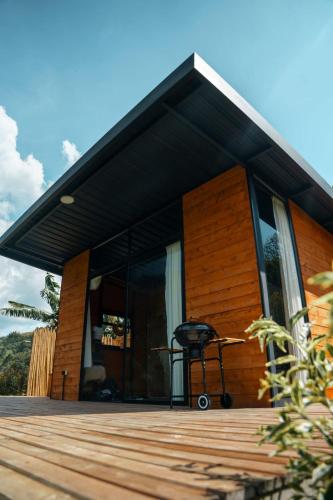 a house with a black roof and a chair on a deck at Rainbow Glamping in Abejorral