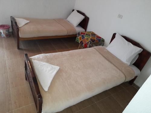 sypialnia z 2 łóżkami i krzesłem w obiekcie Tigana Ka w mieście Naj‘ Tinjār