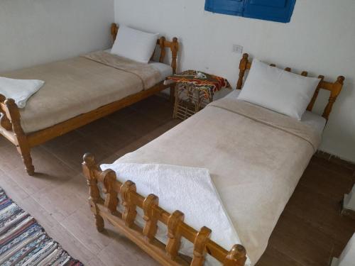 dwa łóżka siedzące obok siebie w pokoju w obiekcie Tigana Ka w mieście Naj‘ Tinjār