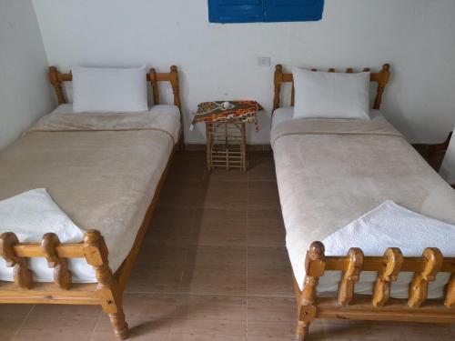 2 łóżka pojedyncze w pokoju ze stołem w obiekcie Tigana Ka w mieście Naj‘ Tinjār