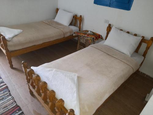 dwa łóżka siedzące obok siebie w pokoju w obiekcie Tigana Ka w mieście Naj‘ Tinjār