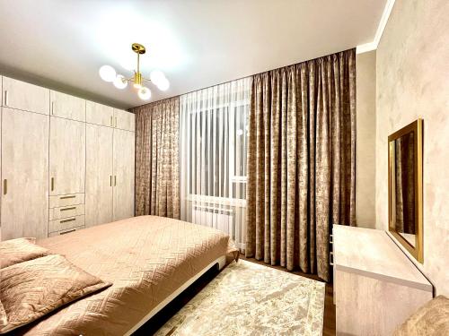 een slaapkamer met een bed en een raam bij Элитная квартира в ЖК “Отау сити” in Simkent