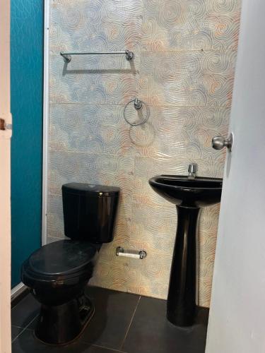 a bathroom with a black toilet and a sink at Punta Arena EcoHostal and EcoFit – Your Eco-Friendly Oasis 01 in Cartagena de Indias