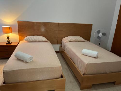 two beds in a small bedroom with a lamp at Nerys House in São Filipe
