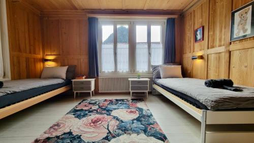 Zimmer mit 2 Betten, einem Fenster und einem Teppich in der Unterkunft Mountain Holiday in Wimmis