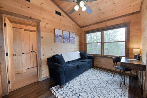 a living room with a black couch in a wooden room at The Lazy K - Mountain view, hot tub, fire pit, games in Blue Ridge
