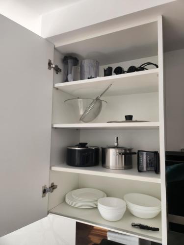 a white pantry with plates and pots and pans at Słoneczny Apartament Warsaw Spire in Warsaw