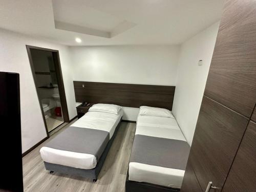 a room with two beds and a mirror at Hotel Expo Hotel Ferial in Bogotá