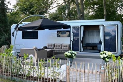 a blue van with a couch and an umbrella at Dreamer Luxus-Caravan am Achterwasser, Lütow in Lütow