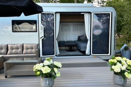 a white van with a couch and a table and flowers at Dreamer Luxus-Caravan am Achterwasser, Lütow in Lütow