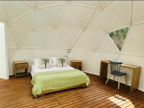 a room with a bed and a chair in a tent at Rainbow Glamping in Abejorral