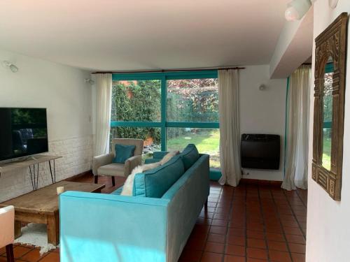 a living room with a blue couch and a large window at Casa máximo confort con oficina in Campana