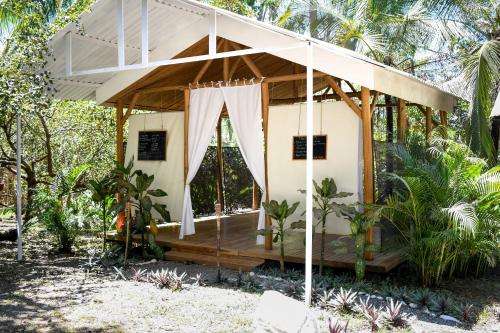 a small house with a wooden porch with a white canopy at Cuatro Vientos Lodge & Apartments in Santa Teresa Beach