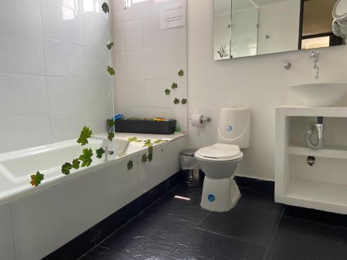 a bathroom with a toilet and a bath tub with plants at Hotel Vesta Boutique in Neiva