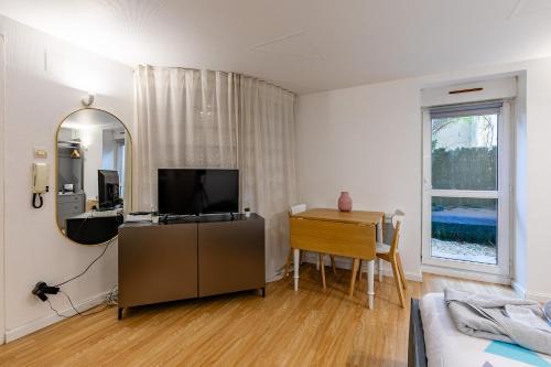 a living room with a television and a table and a mirror at Studio Orangerie & centre in Strasbourg