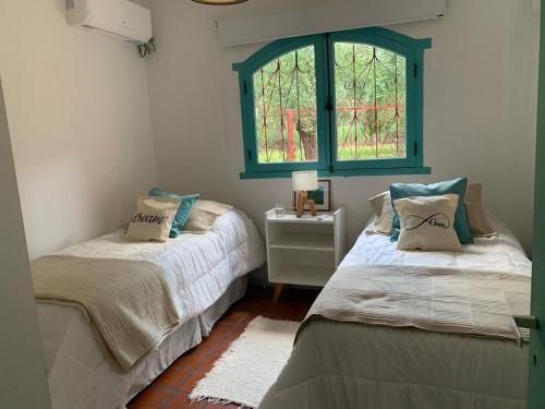 two beds in a room with a window at Casa máximo confort con oficina in Campana