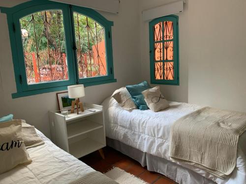 a bedroom with two beds and two windows at Casa máximo confort con oficina in Campana