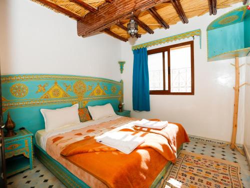 1 dormitorio con 1 cama con colcha de color naranja en Kasbah Du Roches Armed en Imlil