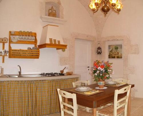 a kitchen with a table with chairs and a sink at Agriturismo Grotta Di Figazzano in Cisternino