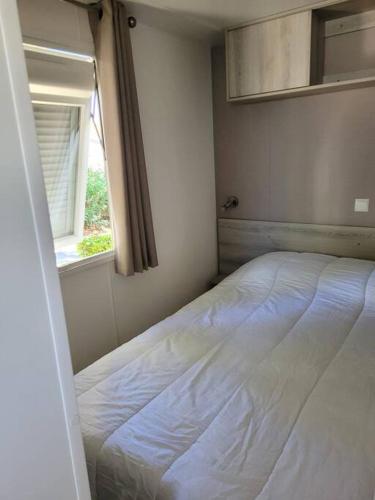 un lit blanc dans une chambre avec une fenêtre dans l'établissement Mobil-home VI 52 à Vias - La Carabasse - Camping Siblu avec piscine, à Vias
