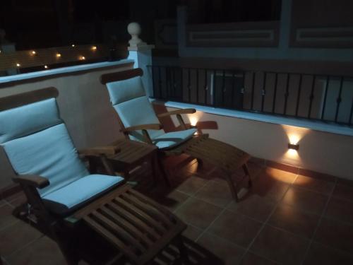two chairs and a bench on a balcony at night at Casa Calypso San Juan de los Terreros in San Juan de los Terreros
