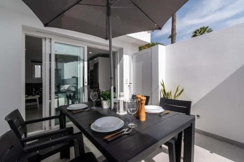 a black table with an umbrella on a patio at Bungalow con piscina comunitaria y terraza privada in Chayofa