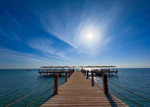 une jetée en bois avec des parasols sur l'eau dans l'établissement 5-BRS Villa Steps from Beach Cozy vibes, à Ain Sokhna