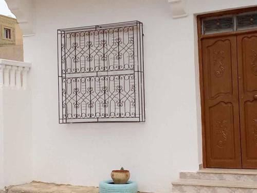 żelazną bramą na białej ścianie obok drzwi w obiekcie Appartement Chebbi w mieście Tauzar