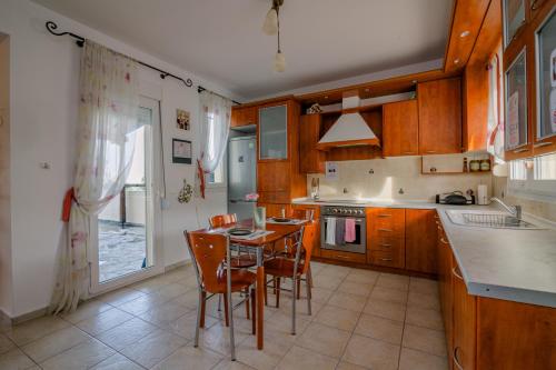 una cocina con armarios de madera, mesa y sillas en Panos house en Chanioti