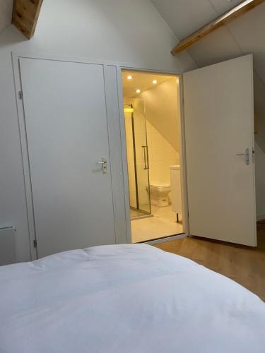 a bedroom with a white bed and a bathroom at Villavento in Hoofddorp